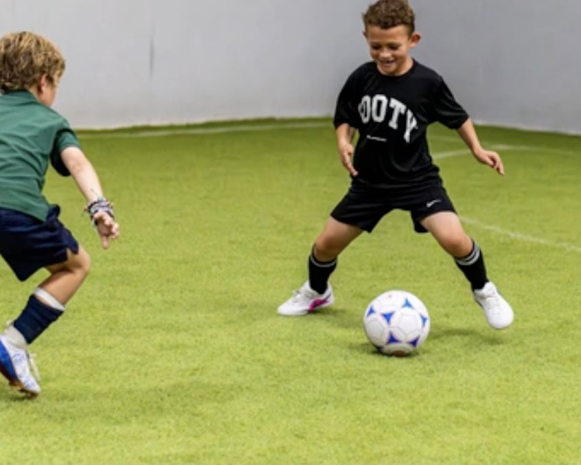 Two young players competing for the ball at a clinic